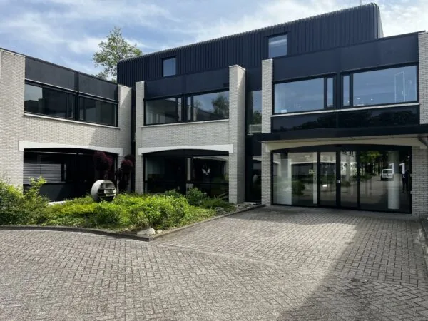 Modern kantoorgebouw aan de Burgemeester Verderlaan 11 met grote ramen en een betegelde oprit.